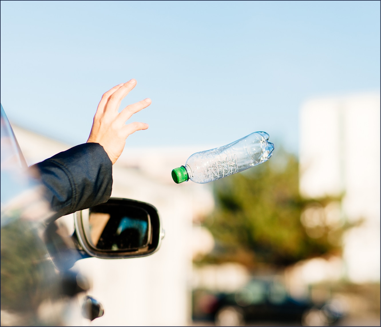  Main jetant une bouteille en plastique par la fenêtre d'une voiture.